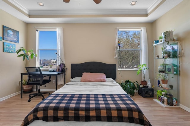 bedroom featuring ceiling fan, a tray ceiling, and multiple windows