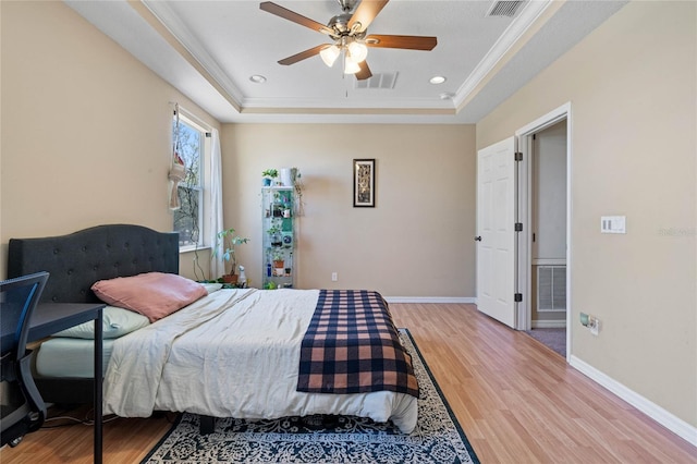 bedroom featuring wood-type flooring, a raised ceiling, ceiling fan, and crown molding