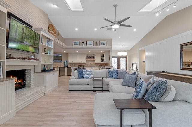 living room featuring a fireplace, light wood-type flooring, ceiling fan, and vaulted ceiling