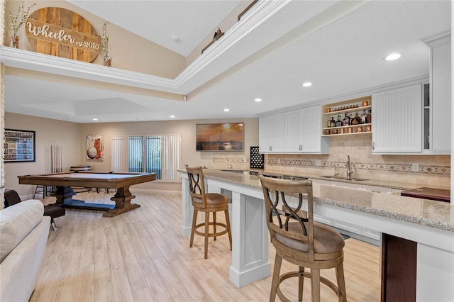 kitchen featuring sink, pool table, white cabinetry, and light stone countertops