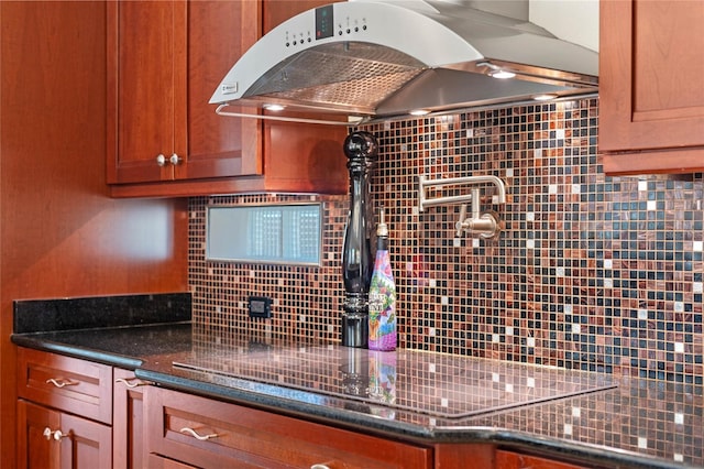 kitchen with exhaust hood, dark stone countertops, and backsplash