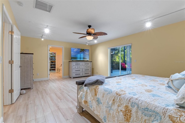 bedroom featuring light hardwood / wood-style floors, track lighting, ceiling fan, a spacious closet, and access to outside