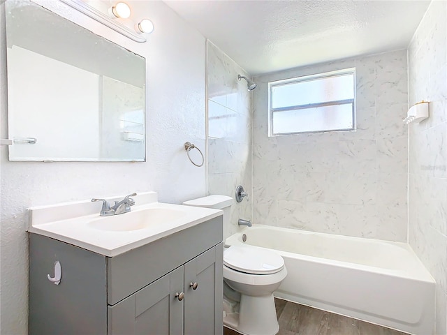 full bathroom featuring toilet, tiled shower / bath, vanity, wood-type flooring, and a textured ceiling