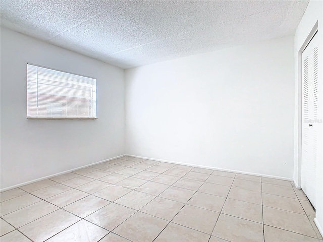 unfurnished room with light tile patterned floors and a textured ceiling