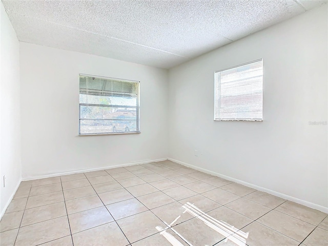 unfurnished room featuring a textured ceiling and light tile patterned floors