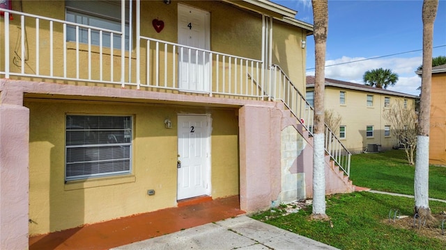 view of exterior entry featuring a yard and central air condition unit