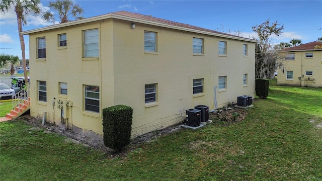 view of property exterior with central AC unit and a lawn