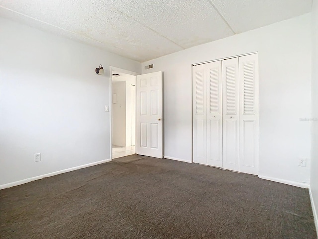 unfurnished bedroom featuring a closet and dark carpet