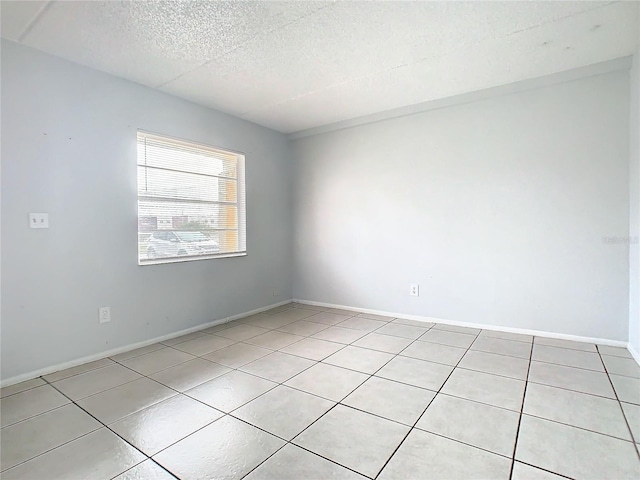 empty room featuring a textured ceiling and light tile patterned floors