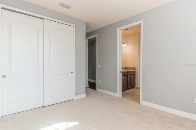 unfurnished bedroom with light colored carpet, a closet, and connected bathroom