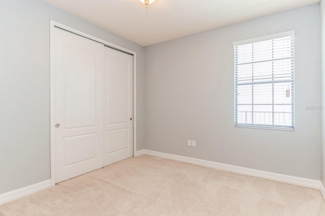 unfurnished bedroom featuring light colored carpet, a closet, and multiple windows