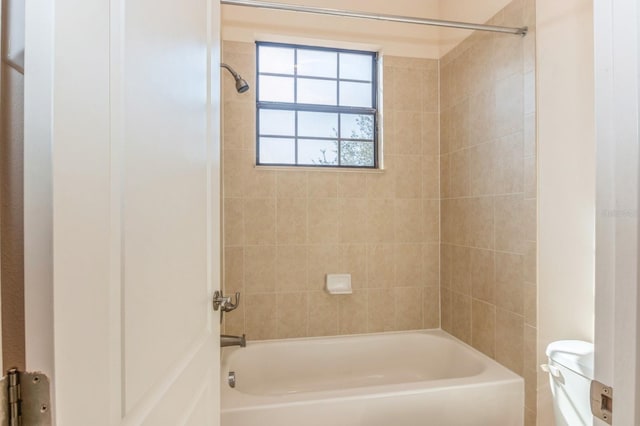 bathroom with toilet and tiled shower / bath