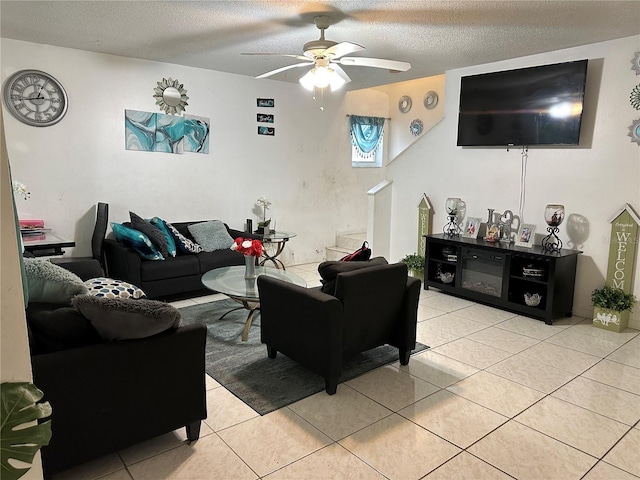 living room featuring a textured ceiling, ceiling fan, and light tile patterned floors