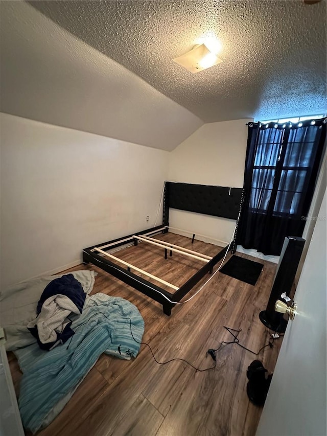 bedroom featuring a textured ceiling, lofted ceiling, and hardwood / wood-style flooring