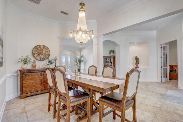 dining space with a chandelier, crown molding, french doors, and decorative columns