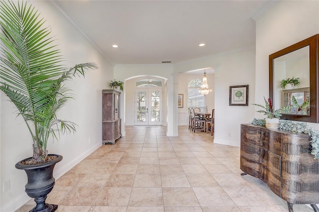 foyer entrance with a chandelier, french doors, and ornamental molding