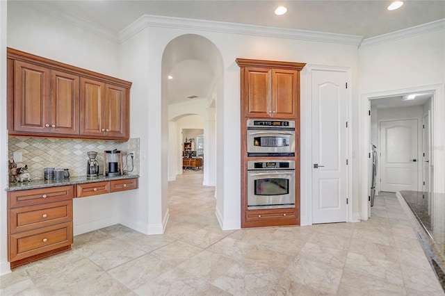 kitchen with backsplash, double oven, light stone countertops, and ornamental molding