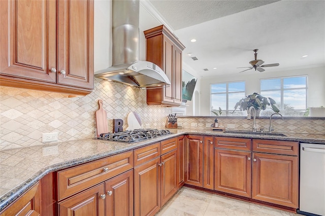 kitchen with light stone countertops, appliances with stainless steel finishes, wall chimney exhaust hood, sink, and ceiling fan