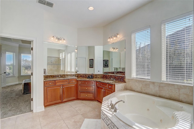 bathroom featuring tile patterned flooring, tiled tub, and vanity