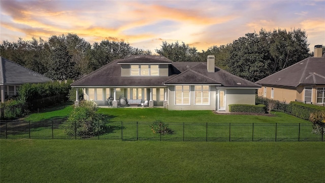 back house at dusk featuring a yard and an outdoor living space