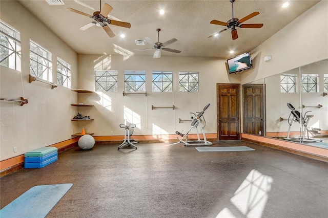 interior space featuring a textured ceiling, ceiling fan, a wealth of natural light, and a high ceiling