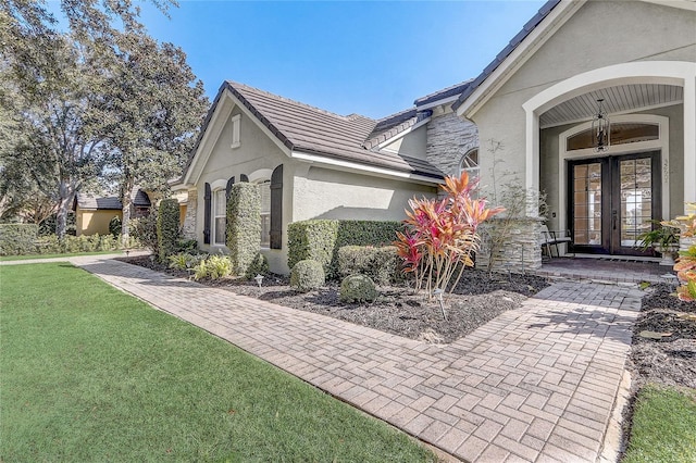 32604 View Haven Ln, Sorrento, FL 32776 - view of property exterior with french doors, stucco siding, stone siding, a yard, and a tile roof