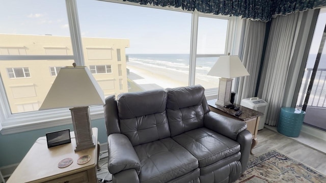 living room featuring a view of the beach, a water view, and hardwood / wood-style floors