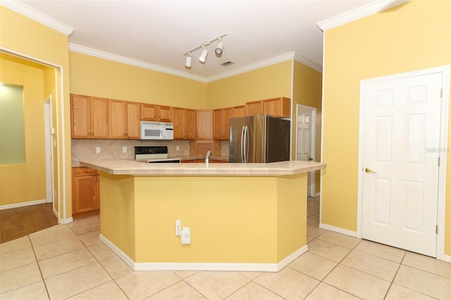 kitchen with a center island with sink, tile counters, range with electric stovetop, and stainless steel fridge