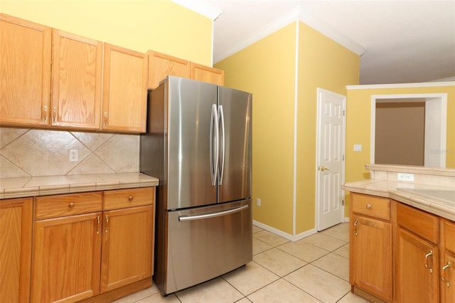 kitchen featuring ornamental molding, light tile patterned floors, stainless steel fridge, and backsplash