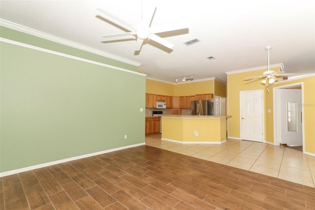 unfurnished living room with rail lighting, ceiling fan, and crown molding