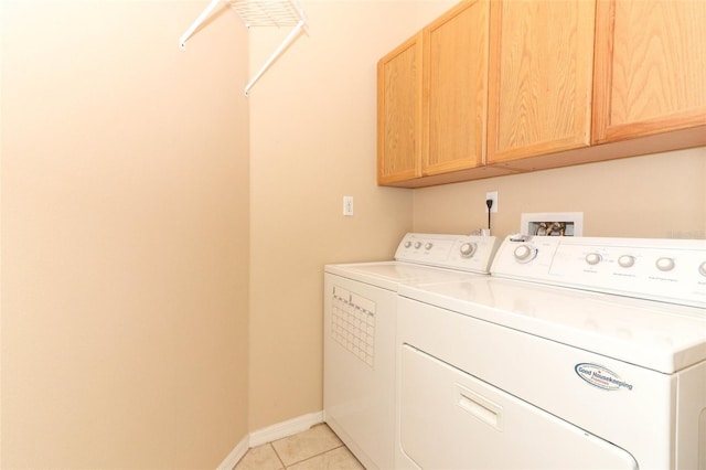 laundry area featuring cabinets, light tile patterned floors, and washer and clothes dryer