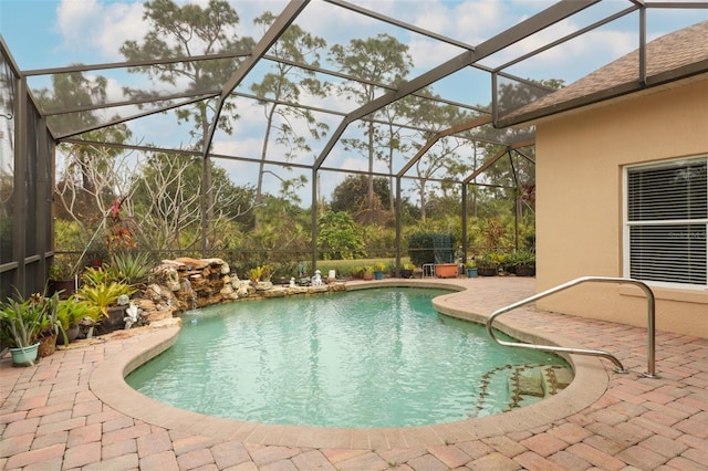 view of pool with pool water feature, glass enclosure, and a patio area