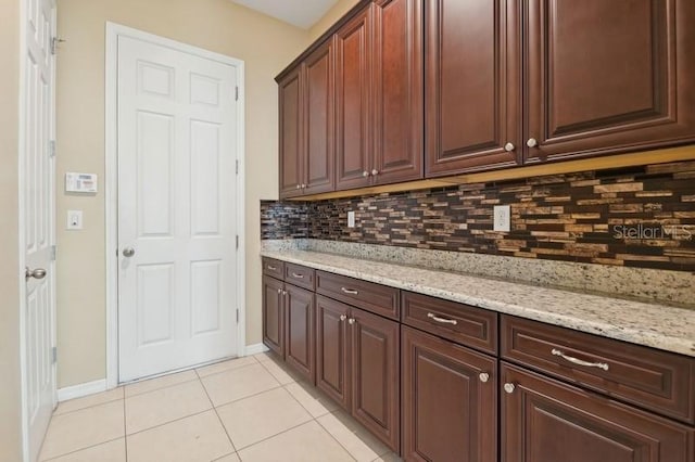 kitchen featuring light tile patterned floors, backsplash, and light stone counters