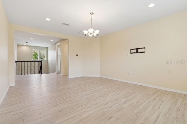 spare room with a chandelier and light hardwood / wood-style floors