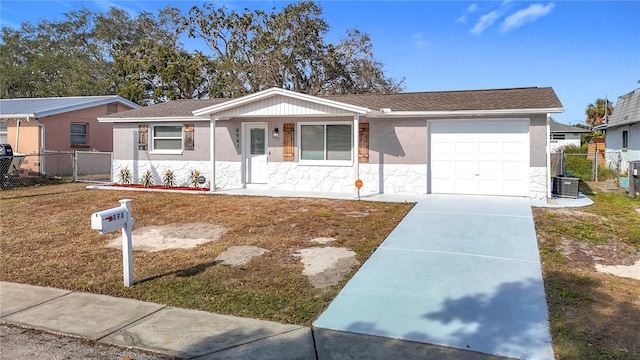 ranch-style home featuring a garage, central air condition unit, and a front lawn