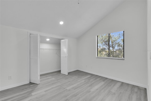 unfurnished bedroom featuring a closet, lofted ceiling, and light hardwood / wood-style flooring