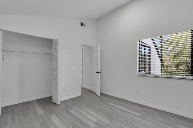 unfurnished bedroom with a closet, lofted ceiling, and light hardwood / wood-style flooring