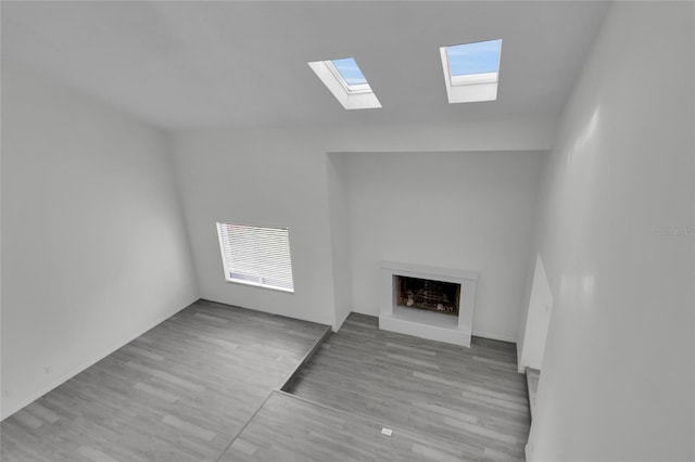 unfurnished living room with light wood-type flooring, a healthy amount of sunlight, and vaulted ceiling