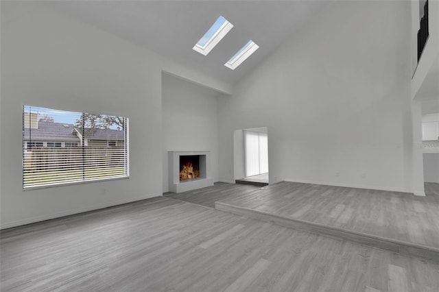 unfurnished living room featuring a high ceiling, light hardwood / wood-style flooring, and a healthy amount of sunlight