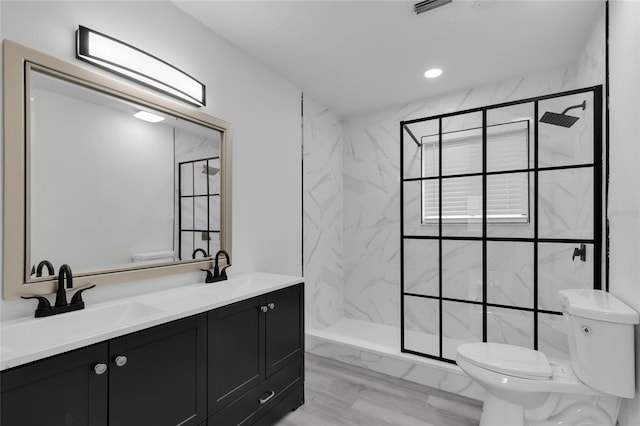 bathroom featuring toilet, vanity, tile walls, and a tile shower