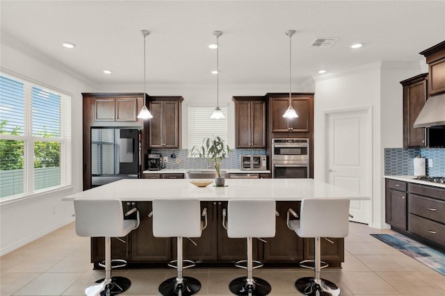 kitchen featuring dark brown cabinets, light tile patterned floors, hanging light fixtures, and a center island