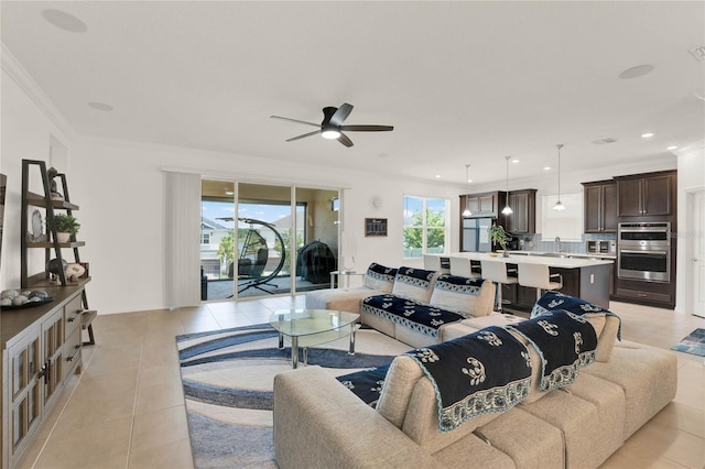 tiled living room with ornamental molding and ceiling fan