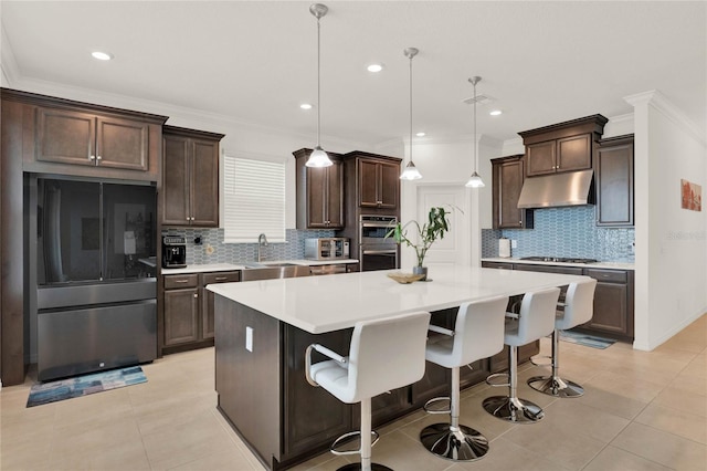 kitchen with a breakfast bar area, stainless steel appliances, a kitchen island, sink, and decorative light fixtures