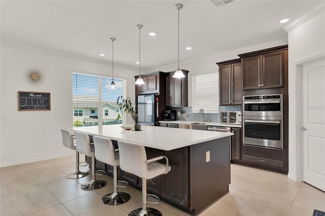 kitchen with refrigerator, pendant lighting, a center island, a breakfast bar area, and stainless steel double oven