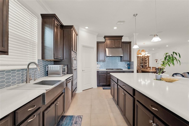 kitchen featuring pendant lighting, tasteful backsplash, ornamental molding, light tile patterned flooring, and dark brown cabinets