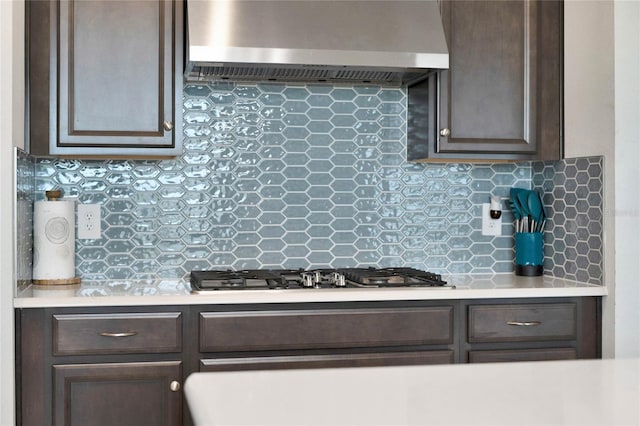 kitchen featuring black gas cooktop, exhaust hood, tasteful backsplash, and dark brown cabinetry