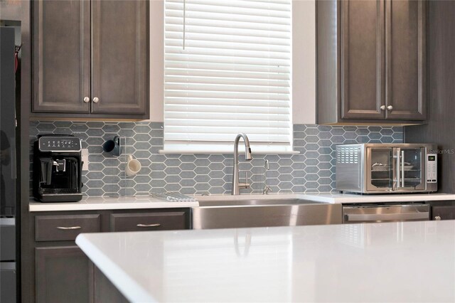 kitchen with stainless steel dishwasher, tasteful backsplash, and dark brown cabinetry