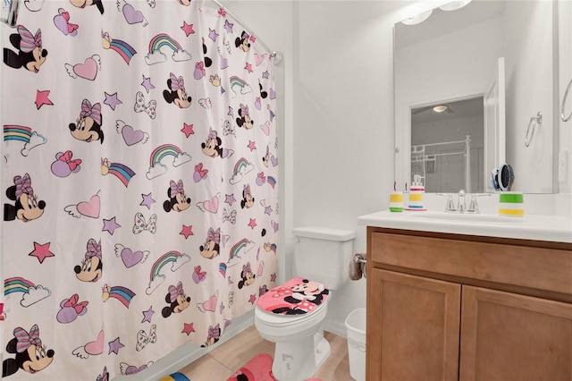 bathroom featuring toilet, vanity, tile patterned floors, and curtained shower