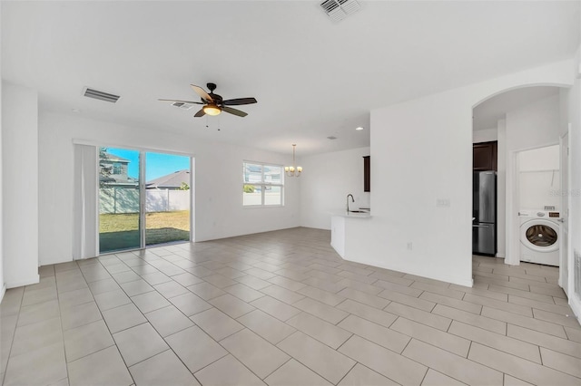 unfurnished living room featuring sink, washer / clothes dryer, ceiling fan with notable chandelier, and light tile patterned floors