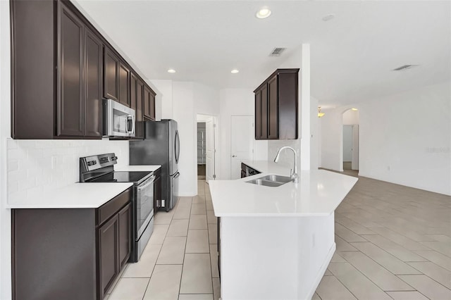 kitchen featuring sink, stainless steel appliances, decorative backsplash, light tile patterned flooring, and dark brown cabinetry